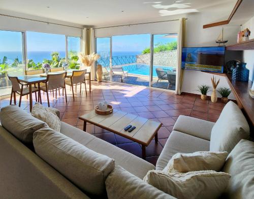 ein Wohnzimmer mit Sofa und Tisch in der Unterkunft Villa Ocean Wave Calheta - Oversized Pool & Stunning Ocean Views in Calheta