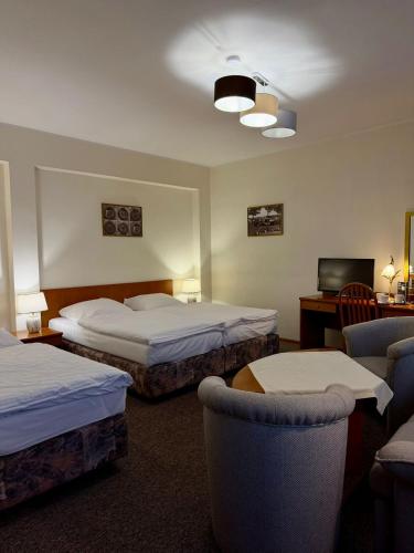 a hotel room with two beds and two chairs at Hotel Dana in Bytów