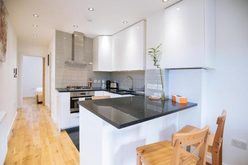 a kitchen with white cabinets and a black counter top at Hidden Gem in Kensington in Finchley