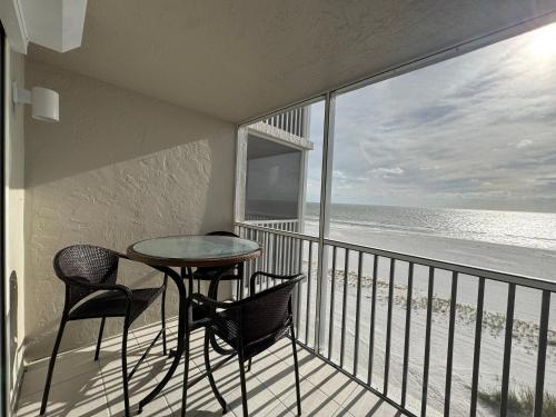 un balcone con tavolo e sedie e l'oceano di Irresistible Beach Life, Spectacular Sunsets - FMB - Condo Sunset Vista - Roelens a Fort Myers Beach