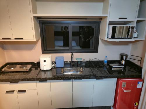 Una cocina con encimera con fregadero y ventana. en Casa Container Oceano, en Foz do Iguaçu