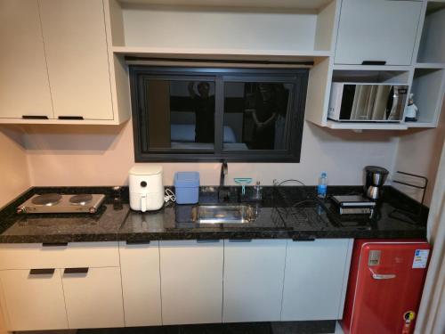 Una encimera de cocina con fregadero y microondas. en Casa Container Oceano, en Foz do Iguaçu