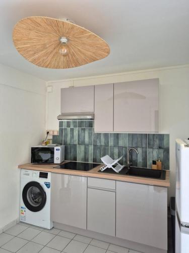 a kitchen with white cabinets and a washer and dryer at Kreyol Chic in Le Gosier