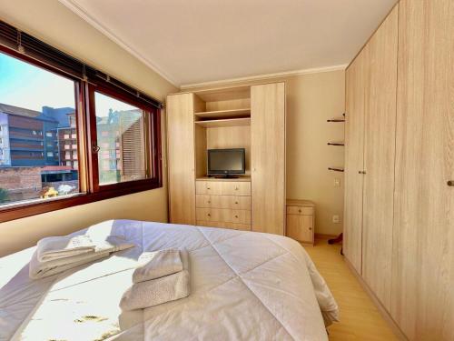 una camera con un letto, una finestra e una TV di Apartamento no centro de Gramado a Gramado