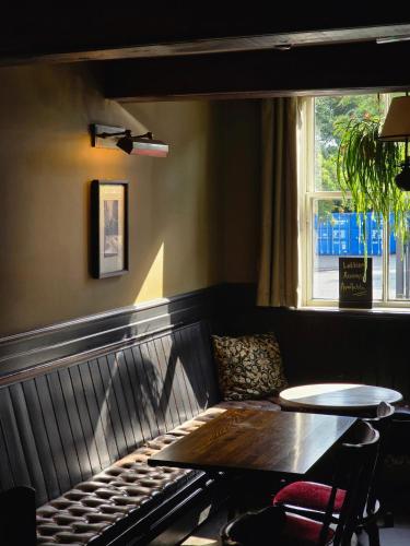 a bench in a restaurant with a table and a window at Red Bull in Stockport