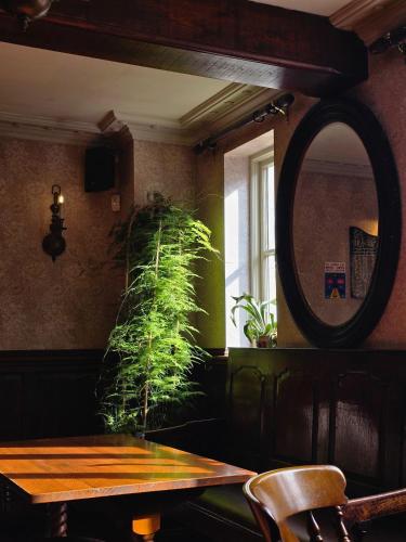 a table and a mirror in a room with a plant at Red Bull in Stockport
