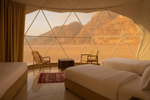 a room with two beds and a large window at Desert Elegance Luxury Bedouin Camp Panoramic View in Disah