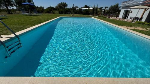 a blue swimming pool with a bench in a yard at Vila Fuzeta Bed&Breakfast in Fuzeta