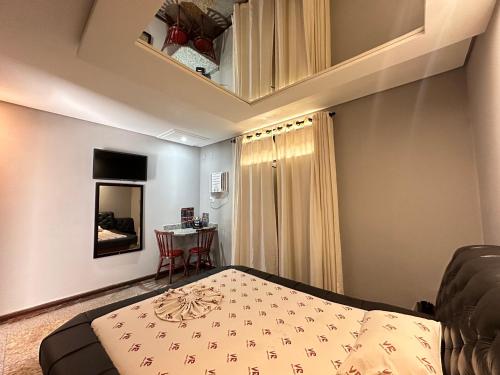 Motel Vitoria Reggia في ساو فيسينتي: غرفة نوم صغيرة مع سرير وطاولة