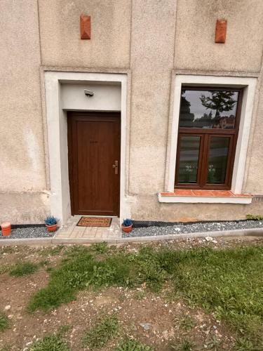 a building with a brown door and two windows at Statek Honezovice ze saunou in Honezovice