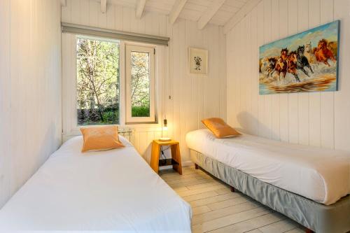 two beds in a room with a window at BOG Nórdica 2 in Villa La Angostura