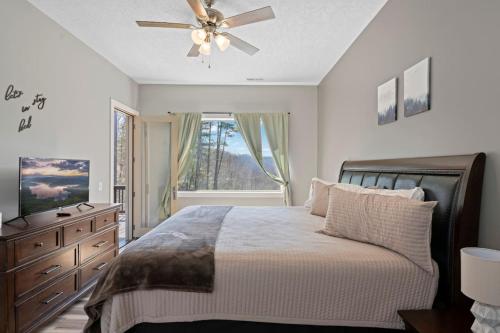 a bedroom with a bed with a ceiling fan and a window at Valley View C - Mountain Retreat, Cozy Balcony, and Grill in Cullowhee