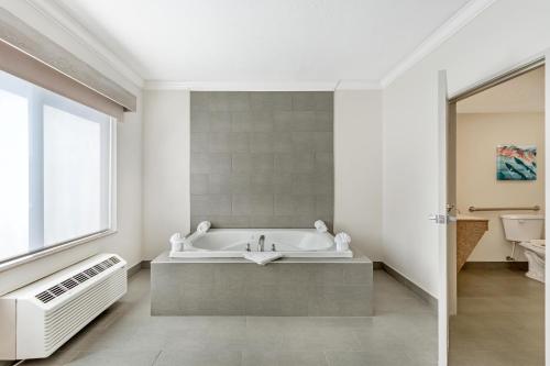 a white bathroom with a bath tub and a window at Best Western Plus Airport Inn & Suites in Salt Lake City