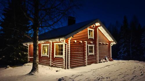 a log cabin in the snow at night at Lapin Villa Hiisi joen rannalla in Ranua