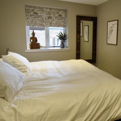 a large white bed in a bedroom with a window at Fife Country Escapes in Cupar