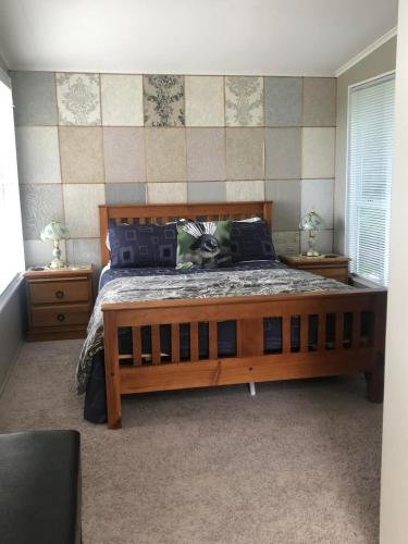 a bedroom with a large wooden bed and two night stands at Fantail at Bluestone Retreat in Leeston