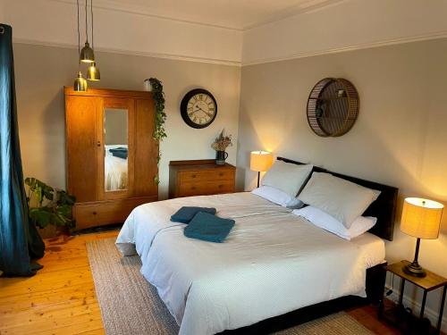 a bedroom with a large bed with a clock on the wall at Room 1, Wedale House in Stow