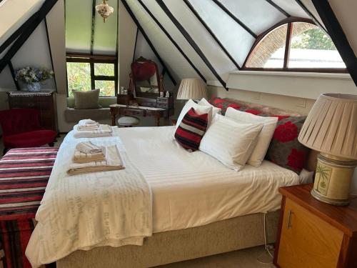 una habitación con una cama grande con sábanas y almohadas blancas en Shire Lodge, en Ciudad del Cabo