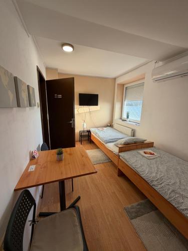 a room with two beds and a table and a desk at Rooms with private Bathroom & Free Parking ''Sobe Zoka,, in Subotica