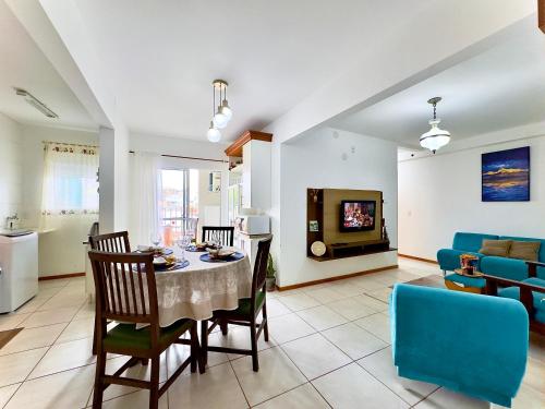 a dining room and living room with a table and chairs at Apto em Barra Velha 340m da PRAIA com SACADA com CHURRASQUEIRA, AR CONDICIONADO WI-FI, PISCINA, PORTARIA 24h, ACADEMIA MINI MERCADO e vaga de GARAGEM in Barra Velha