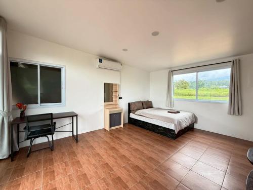 a bedroom with a bed and a desk and a window at Sandy house Pai 2 in Pai