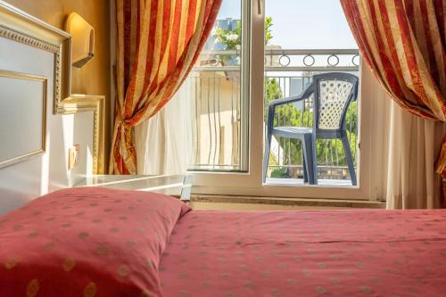 a bedroom with a bed and a window with a chair at Hotel King in Rimini