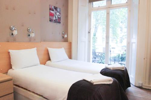 2 camas individuales en una habitación con ventana en Tony's House Hotel, en Londres