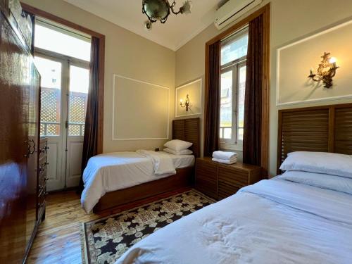 une chambre avec deux lits et deux fenêtres dans l'établissement Authentic 3BR apartment in Downtown, Cairo, au Caire
