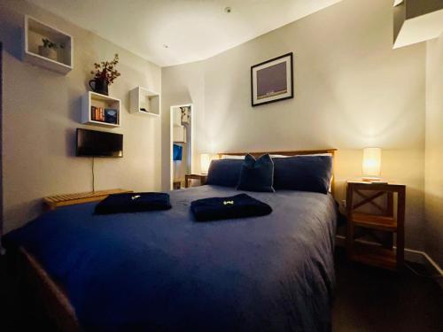 a bedroom with a blue bed with two bags on it at The Wedale Bothy in Stow
