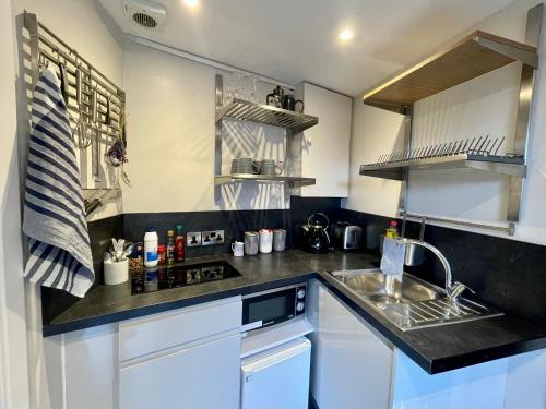 a small kitchen with white cabinets and a sink at The Wedale Bothy in Stow