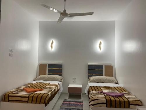 2 camas en una habitación con ventilador de techo en OBAI Nubian Guest House, en Jazīrat Aswān
