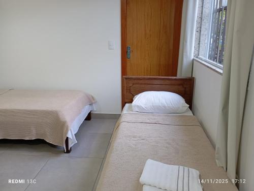 ein kleines Zimmer mit zwei Betten und einem Fenster in der Unterkunft aeroporto e praia loft aconchegante in Vitória