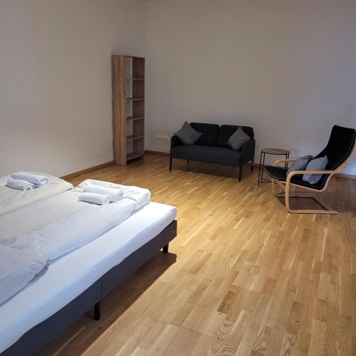 ein Zimmer mit zwei Betten und einem Sessel und einer Couch in der Unterkunft Bahnhofstraße III Apartment in Straubing