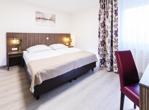 a bedroom with a large bed and a red chair at Pension Altes Backhaus in Herzogenaurach