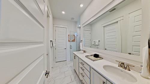 a white bathroom with a sink and a mirror at Settle By The Sea in Inlet Beach