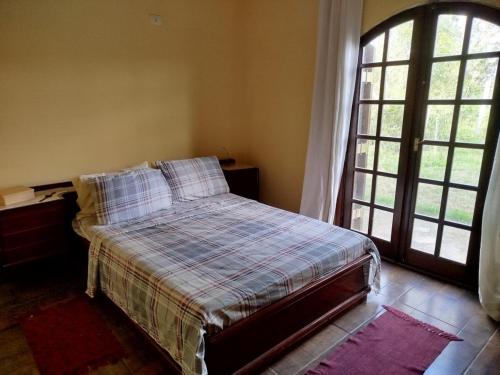 a bedroom with a bed and a large window at Chácara Condomínio Cristal Azul Mairinque in Mairinque