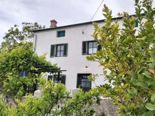 a white house with black windows and trees at Gemütliches Ferienhaus Viskic in Supetarska Draga