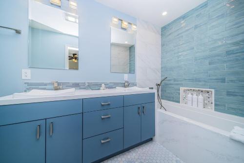 une salle de bain bleue avec un lavabo et une baignoire dans l'établissement Ocean Vista Penthouse 1, à San Diego