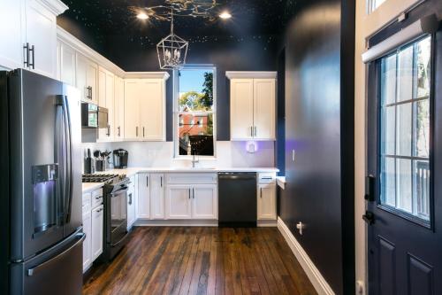 eine Küche mit weißen Schränken und einem schwarzen Kühlschrank in der Unterkunft The Celestial House by StayLage in Soulard