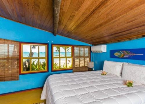 um quarto com uma cama grande com paredes e janelas azuis em Casa Mar em Porto Seguro
