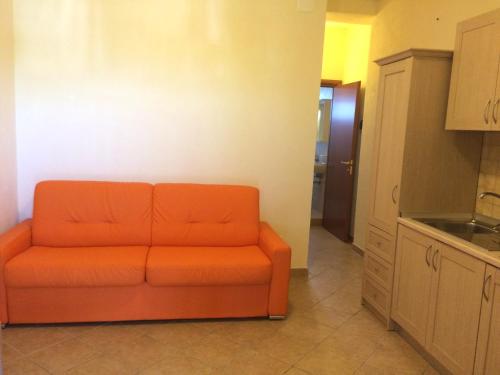 an orange couch sitting in the middle of a kitchen at Summer Holidays Apartments in Foce Varano