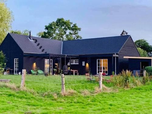 a black house with a field in front of it at Wooden Cottage Near The Baltic Sea in Lensahn