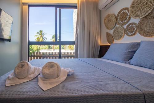 una camera da letto con due asciugamani e un letto con finestra di Triplex 3 Suítes Piscina e Hidro para até 12 pessoas a Tatuamunha