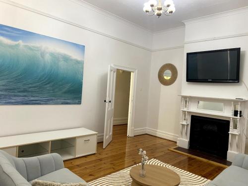 a living room with a tv and a fireplace at Glenelg - Charmer in Glenelg