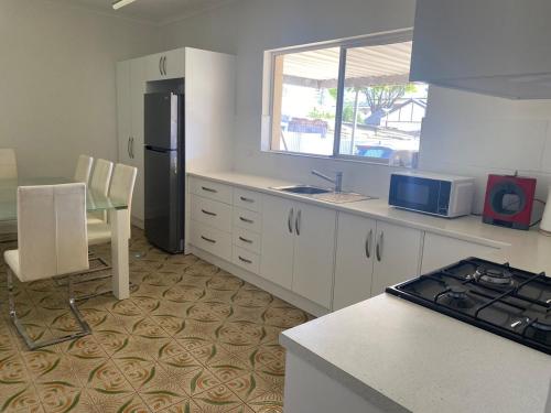 a kitchen with white cabinets and a sink and a refrigerator at Glenelg - Charmer in Glenelg
