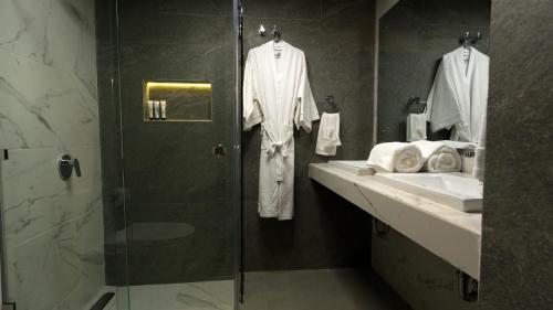 a bathroom with a shower and two sinks and robes at Hotel Tiffany in Flores