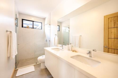 ein weißes Badezimmer mit zwei Waschbecken und einer Toilette in der Unterkunft Casa Peace with salt water pool 4BR 4BR in Tamarindo
