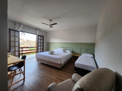 een slaapkamer met een bed, een bank en een tafel bij Pousada Essência de Minas in São Lourenço