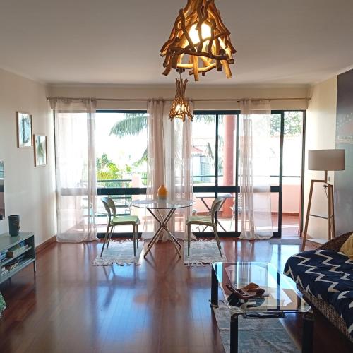 a living room with a table and chairs and a chandelier at Varandas do Funchal Apartment in Funchal