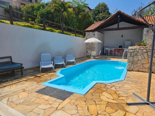 een zwembad in een tuin met stoelen eromheen bij Pousada Essência de Minas in São Lourenço